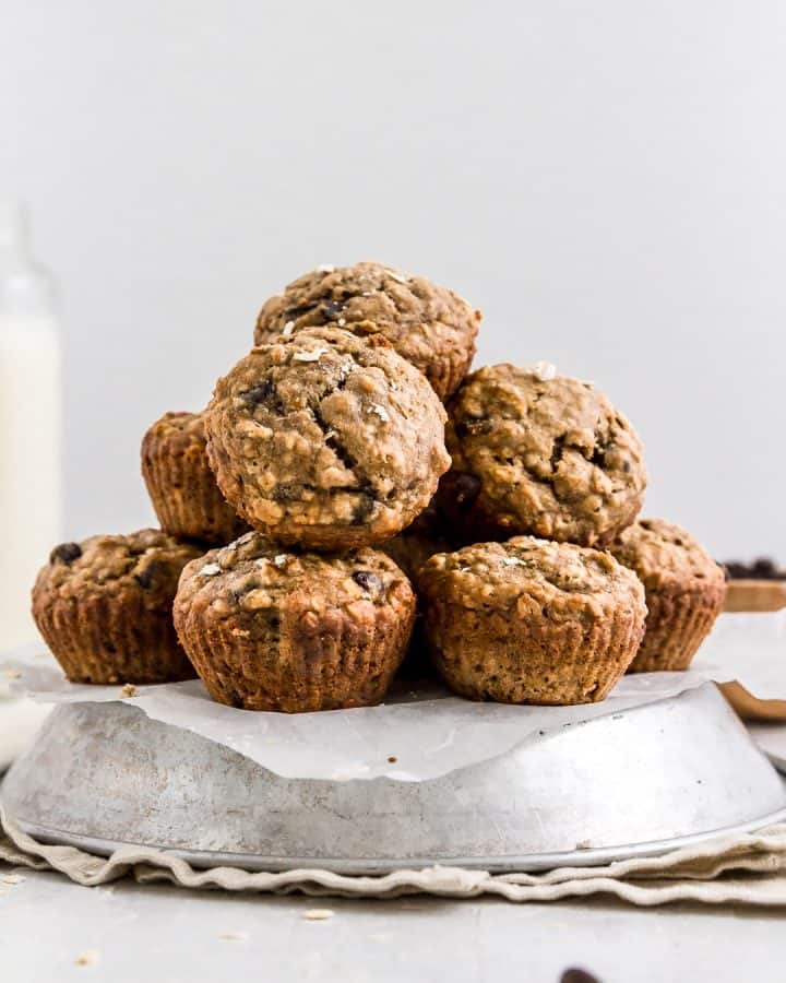 A big pile of healthy banana chocolate chip muffins with a glass of plant milk.